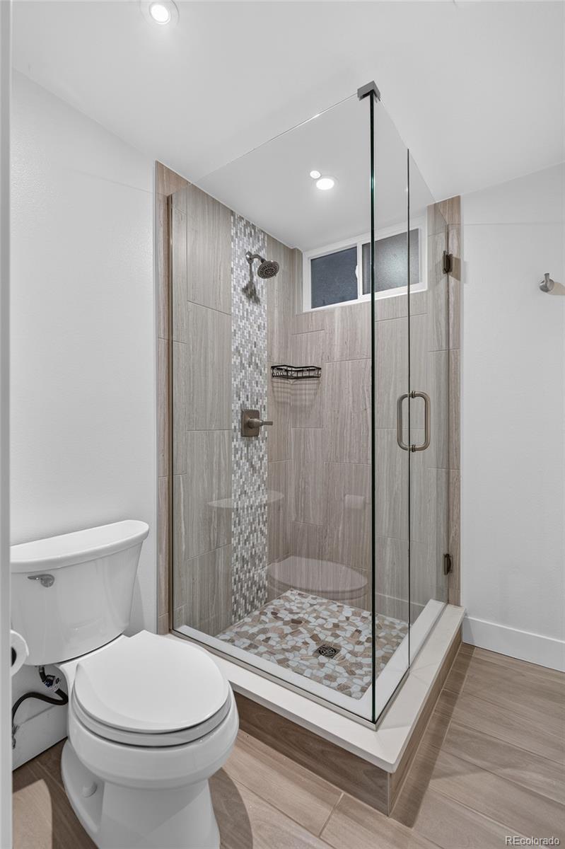 Bathroom with a glass-enclosed tiled shower, pebble mosaic floor, and toilet.