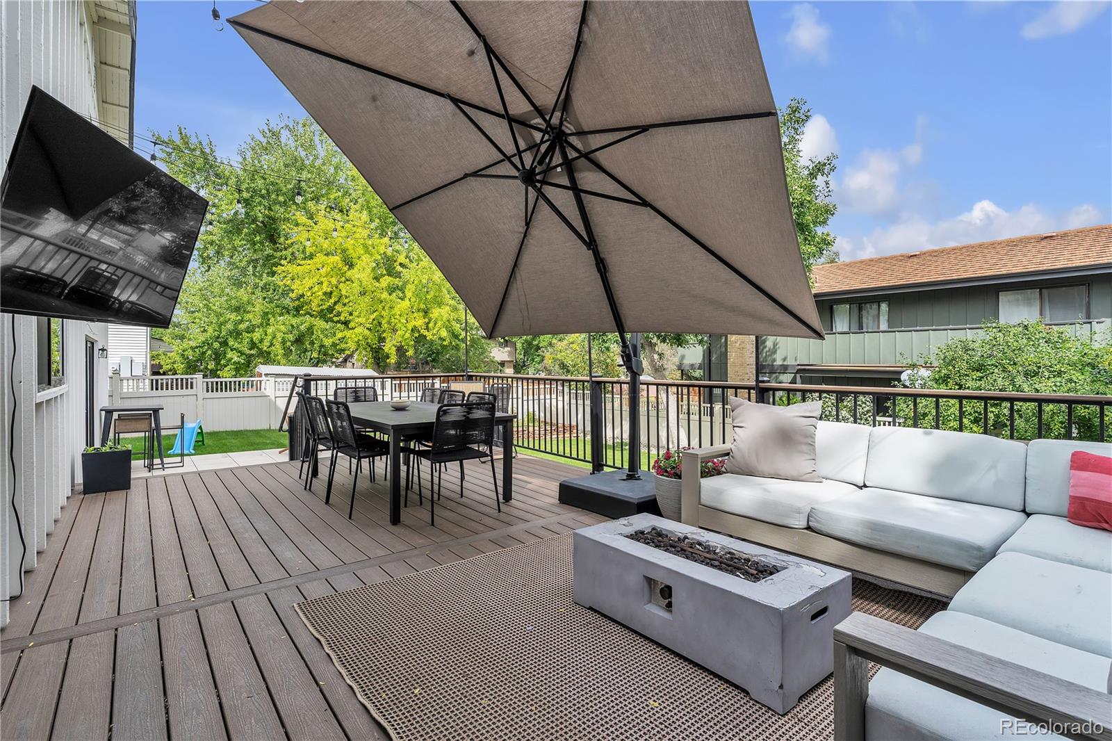 Outdoor deck with umbrella, dining set, cushioned seating, and fire table