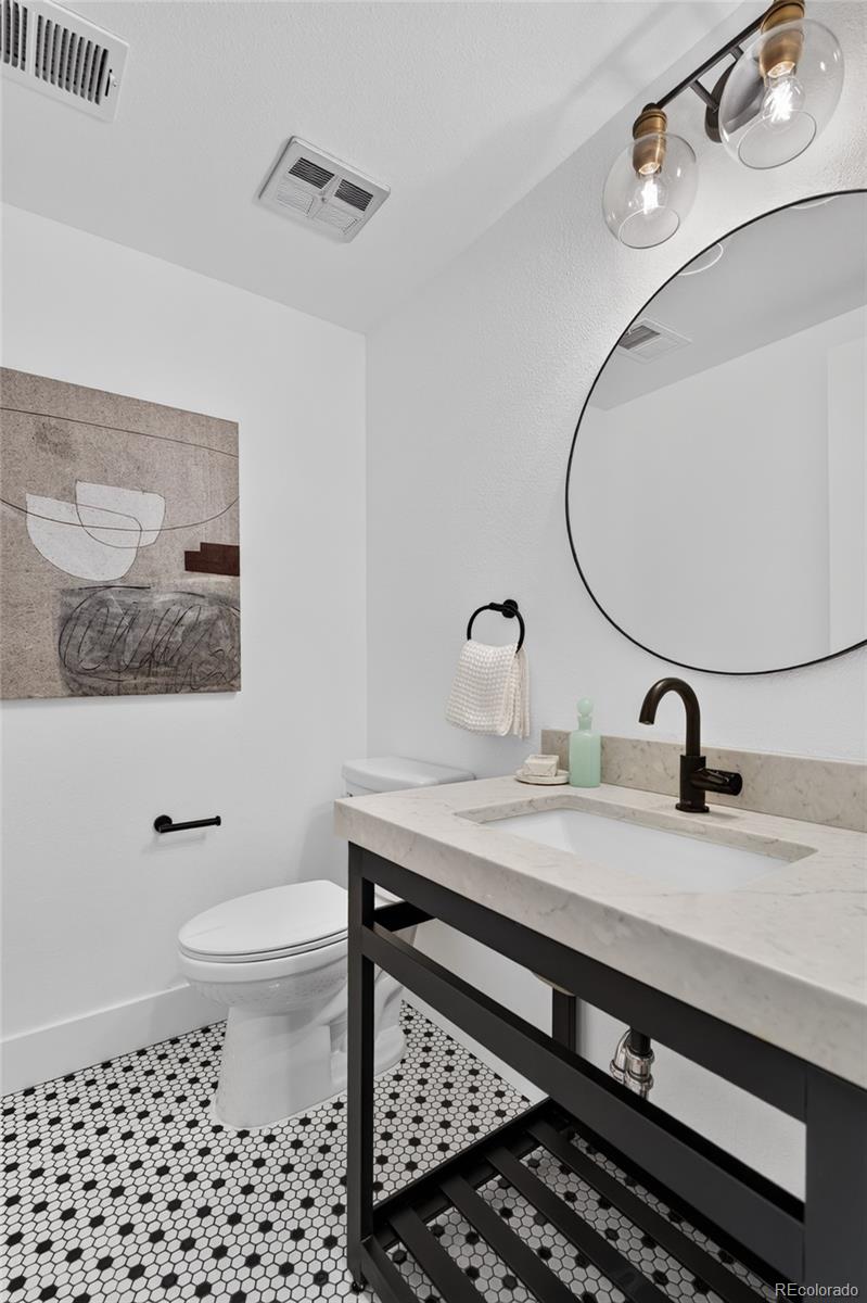 Bathroom with a marble vanity, round mirror, and black-and-white hexagonal tile floor.