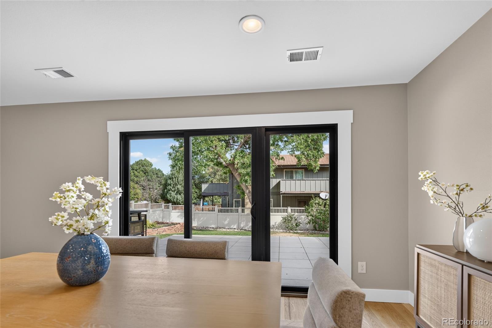 Dining area with sliding glass doors opening to a paved patio and leafy backyard.