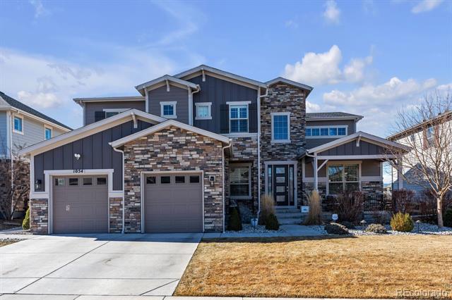 Two-story gray home with stone accents, two garage doors, and a wide driveway.