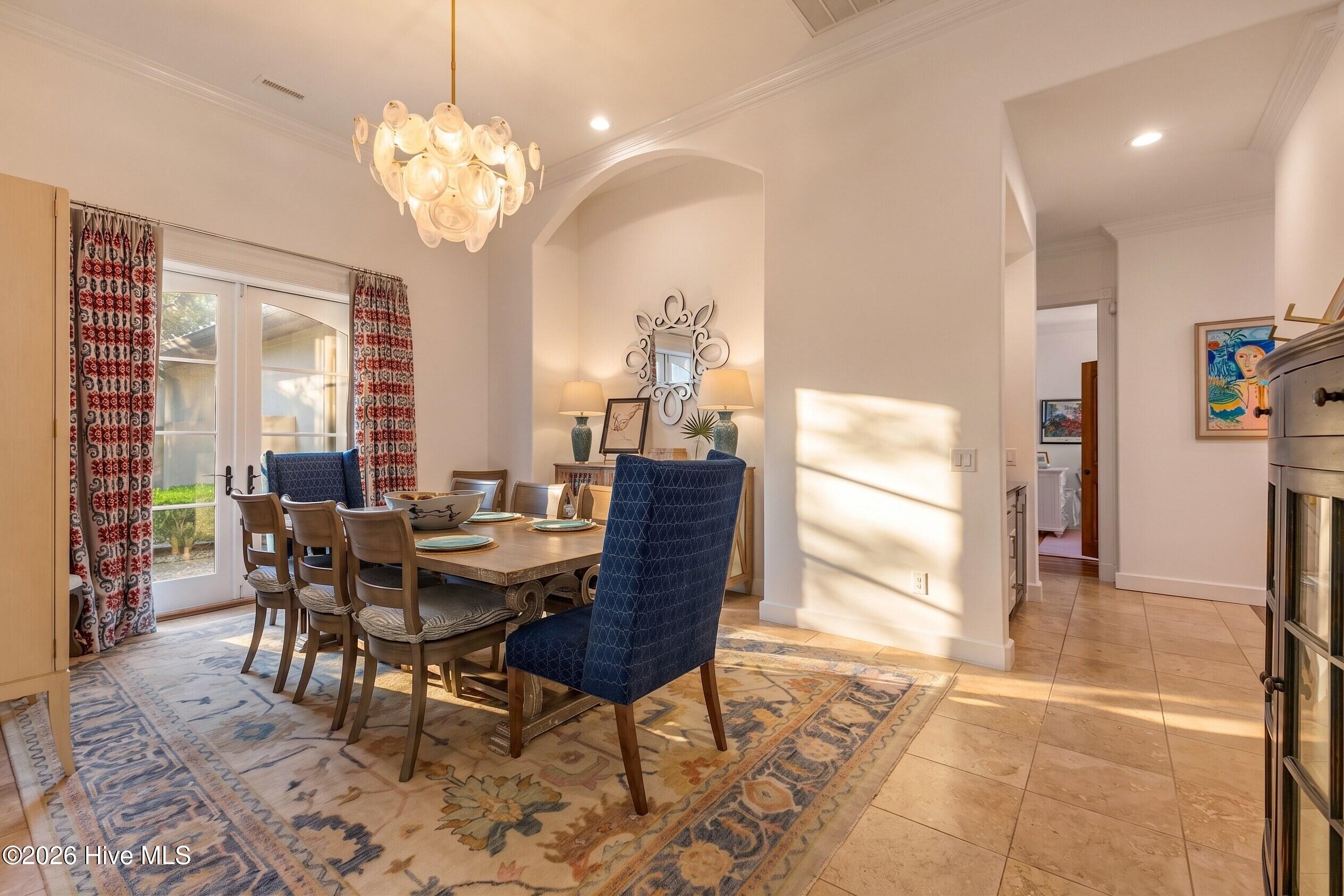 Dining room with a sculptural chandelier, patterned rug, and glass doors opening to the yard.