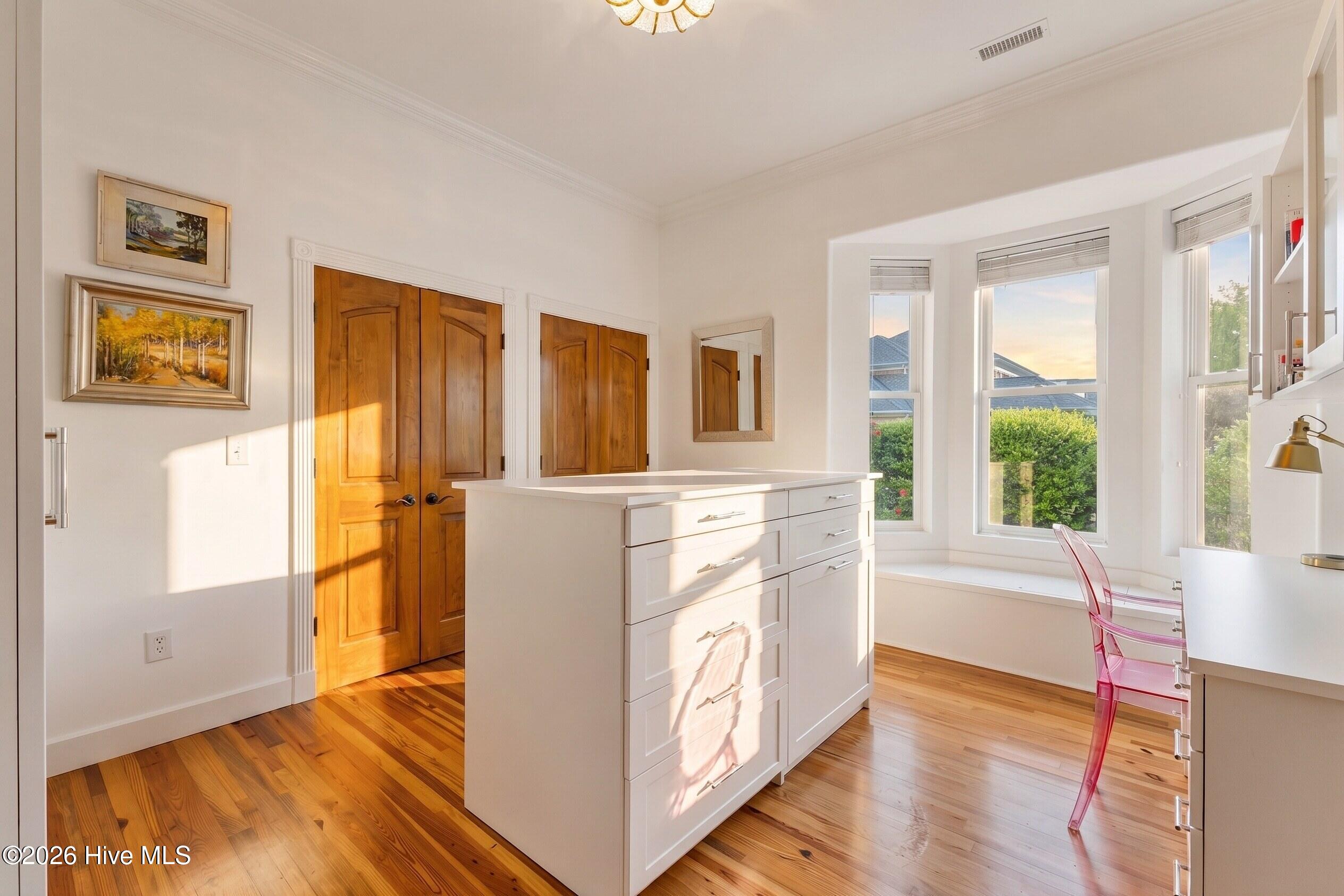 Bright kitchen with a white island, warm wood floors, and a sunny bay window.
