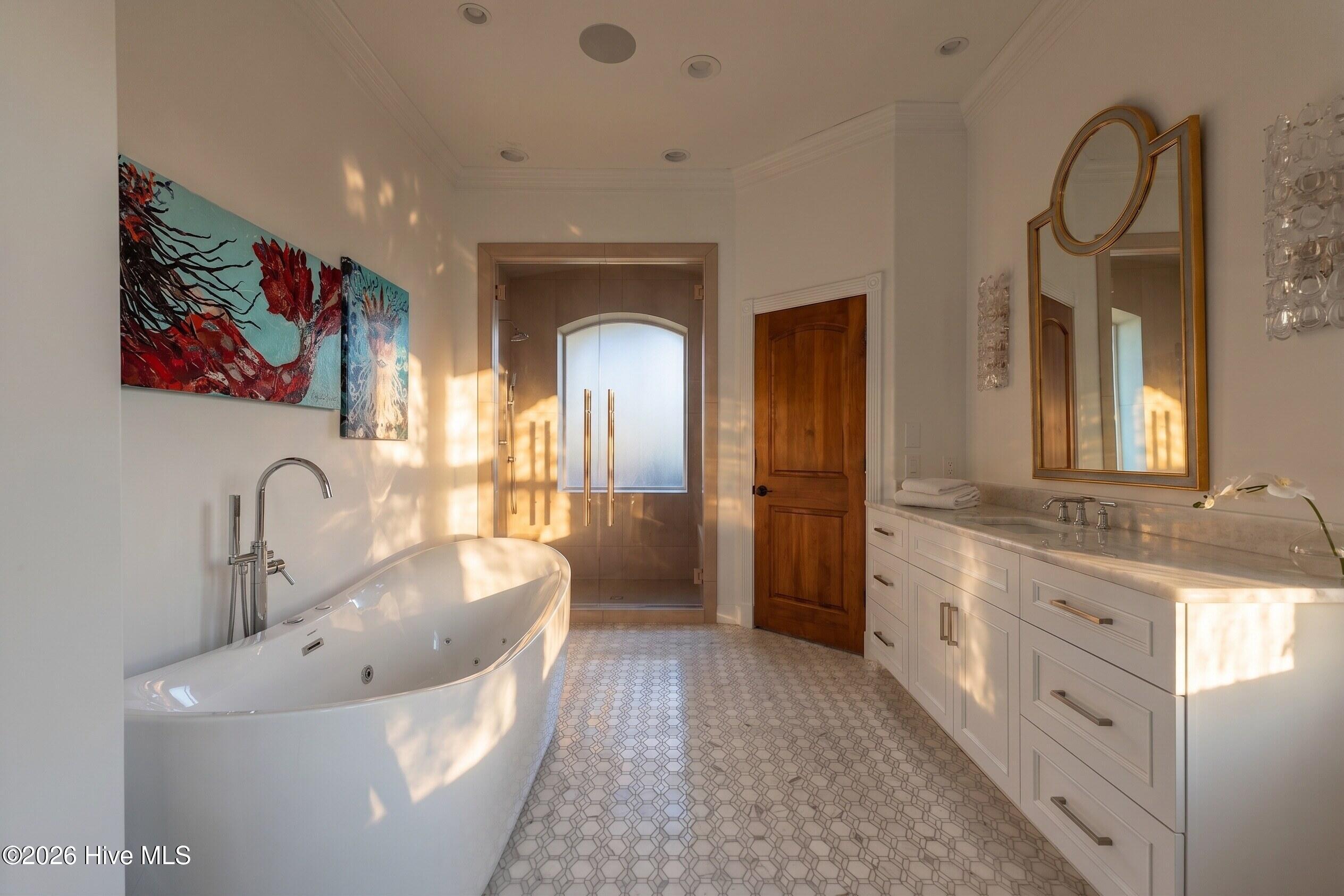 Bathroom with a freestanding tub, glass shower, double vanity, and patterned tile floor.