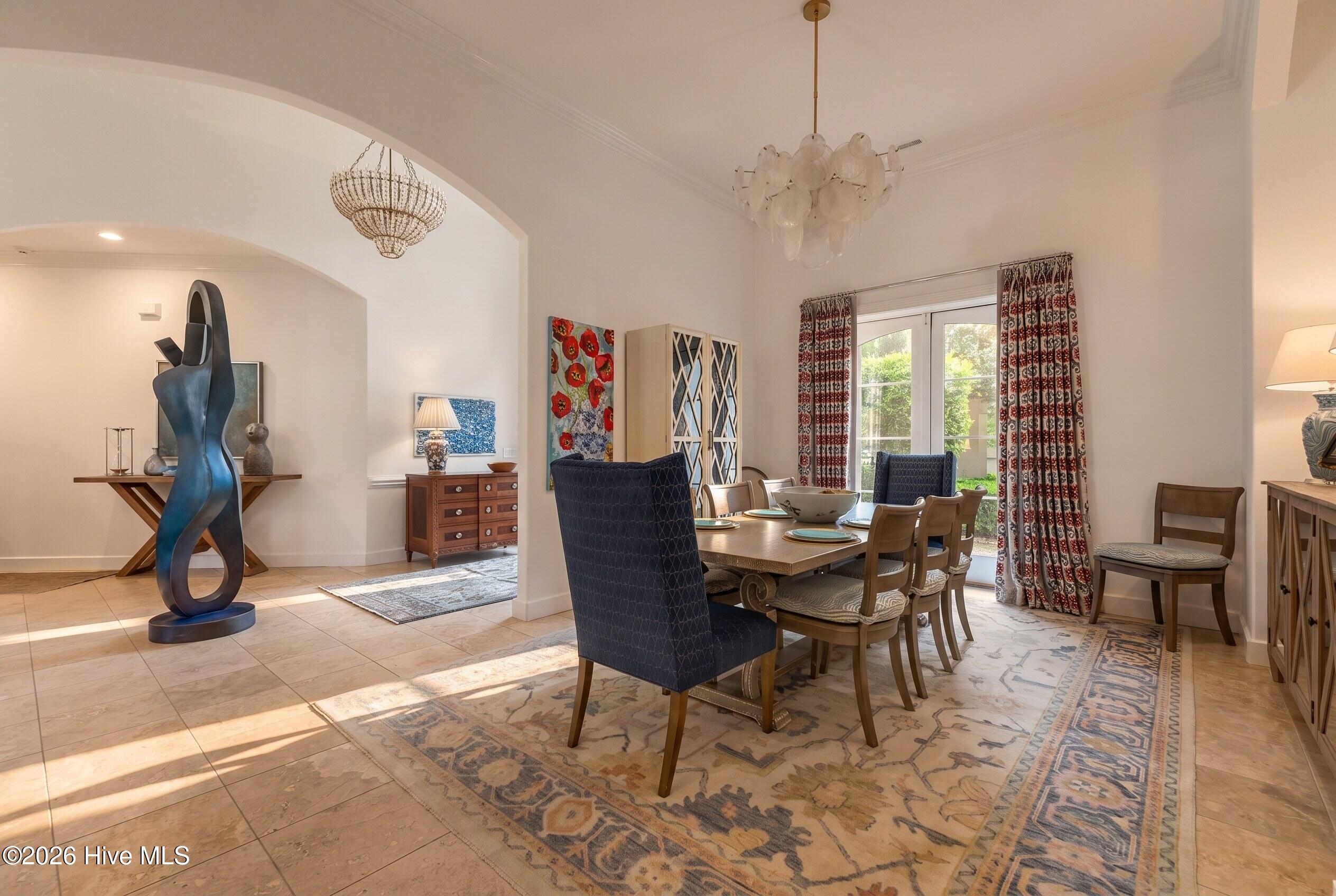 Dining room with a wooden table, patterned rug, glass doors, and a large blue sculpture.