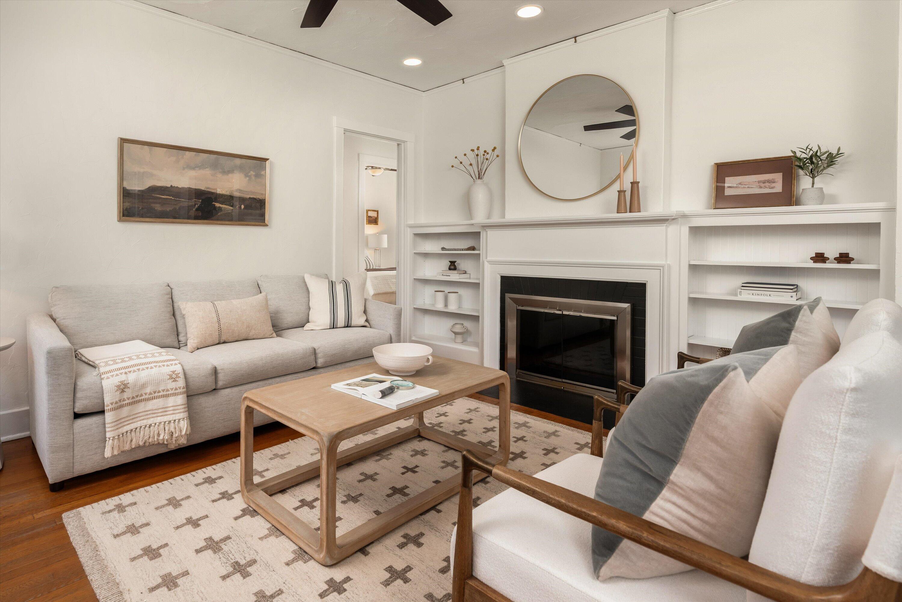 Living room with pale sofas, a patterned rug, and a fireplace framed by built-in shelving.