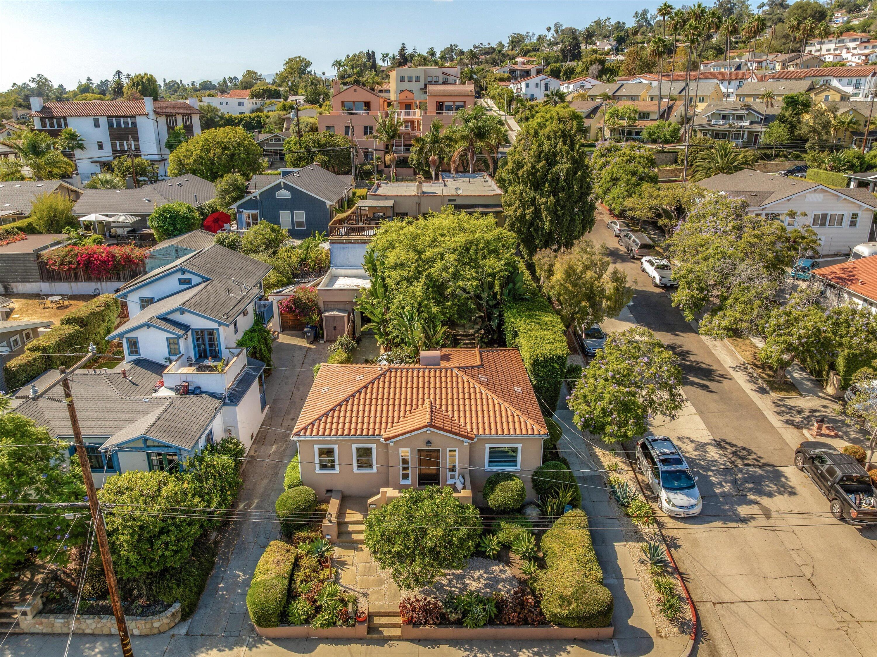 Aerial view of a terracotta-roofed home with a landscaped yard and tree-lined neighborhood street.