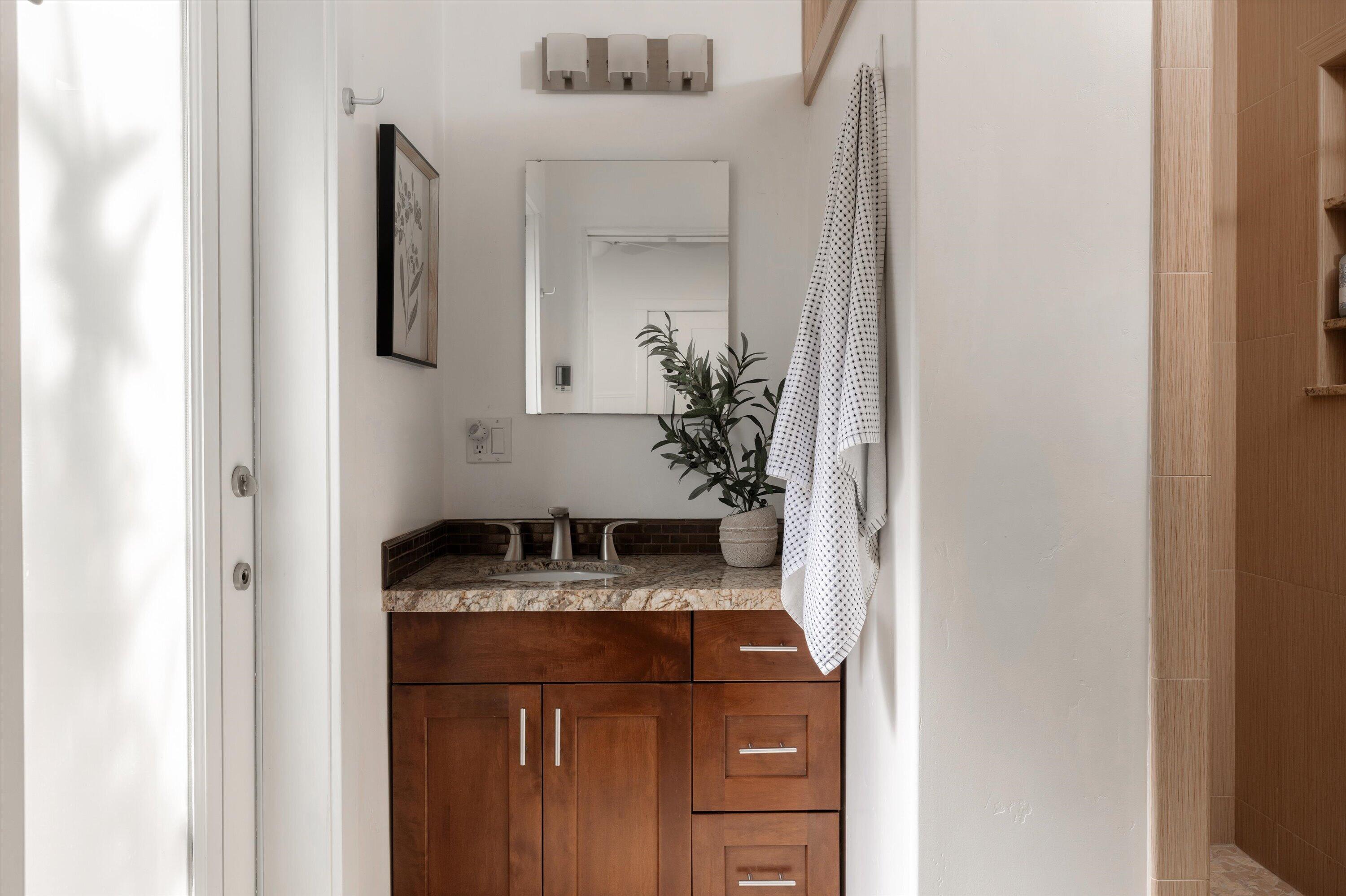 Bathroom vanity with a stone countertop, dark wood cabinetry, and a patterned towel.