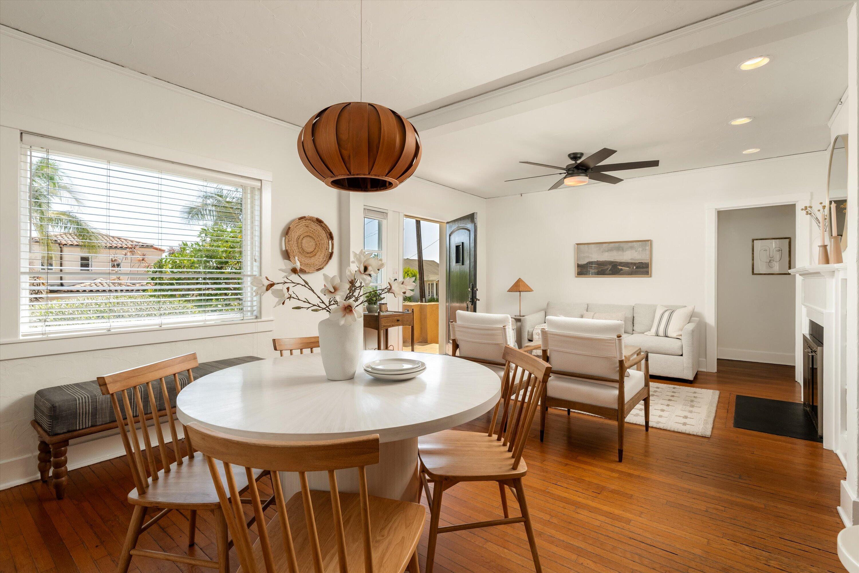 Open-plan dining and living room with hardwood floors, a round table, and a white sofa.