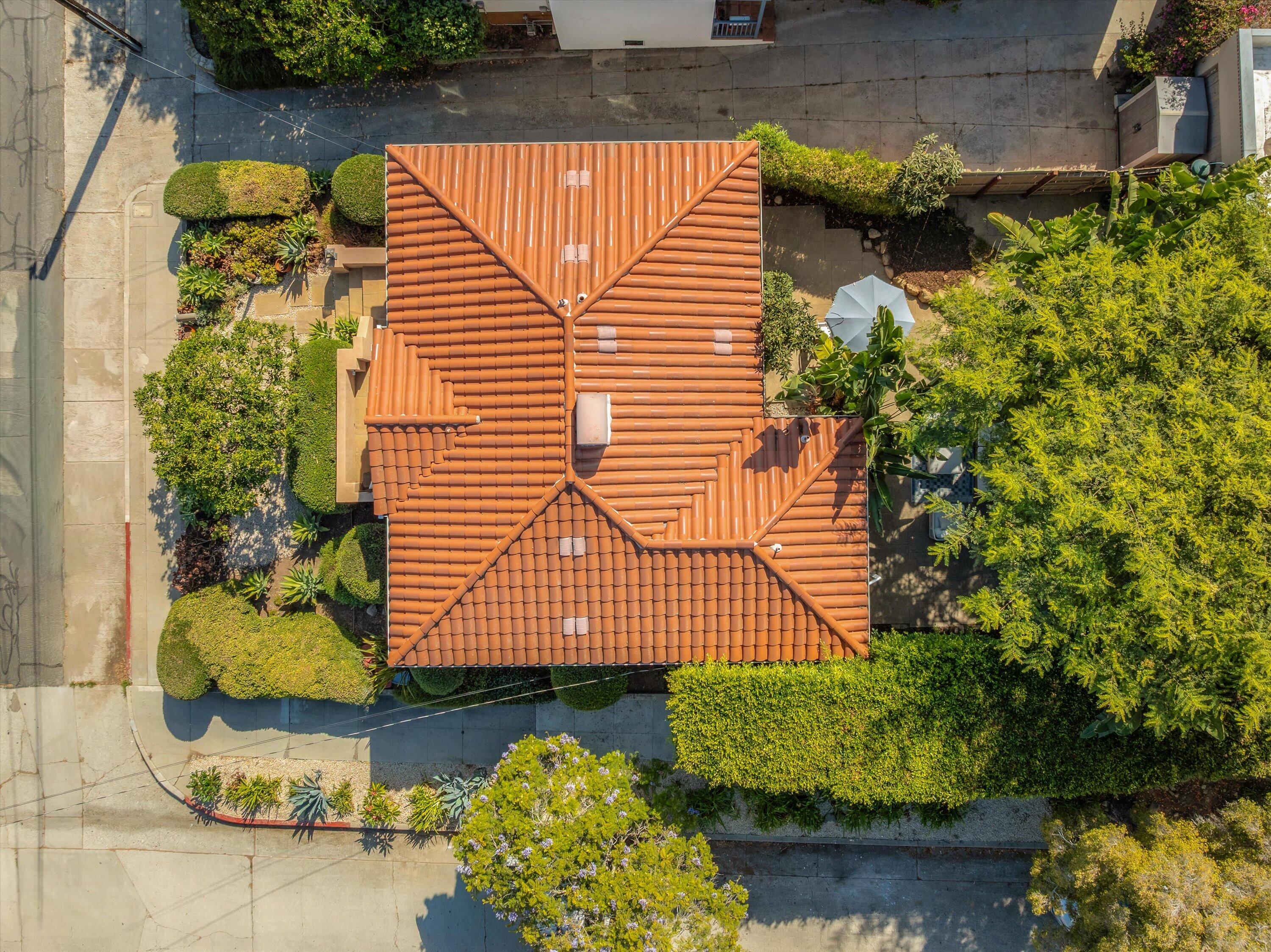 Aerial view of a terracotta-tile-roofed home surrounded by landscaped gardens and sidewalks.