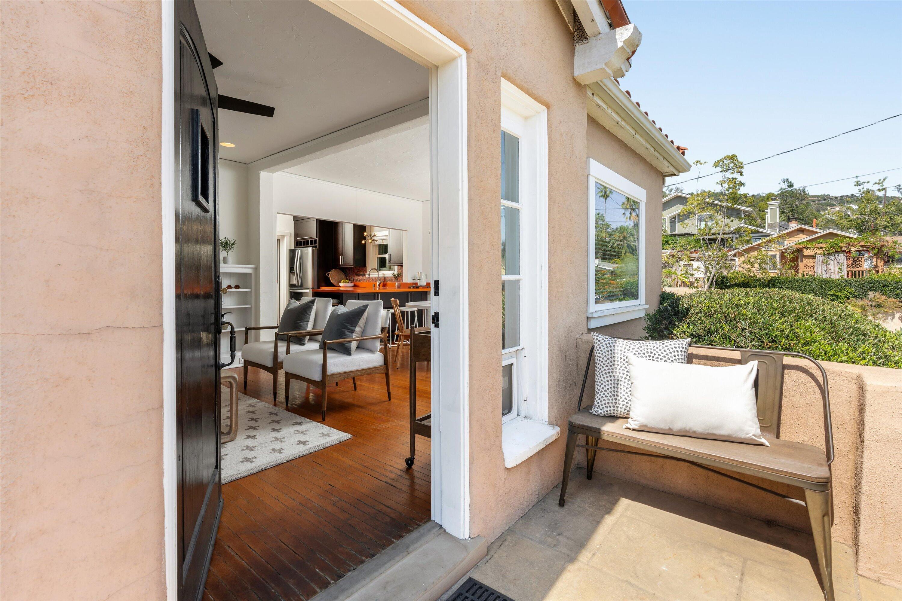 Furnished patio with a cushioned bench beside an open doorway to the living room and kitchen.