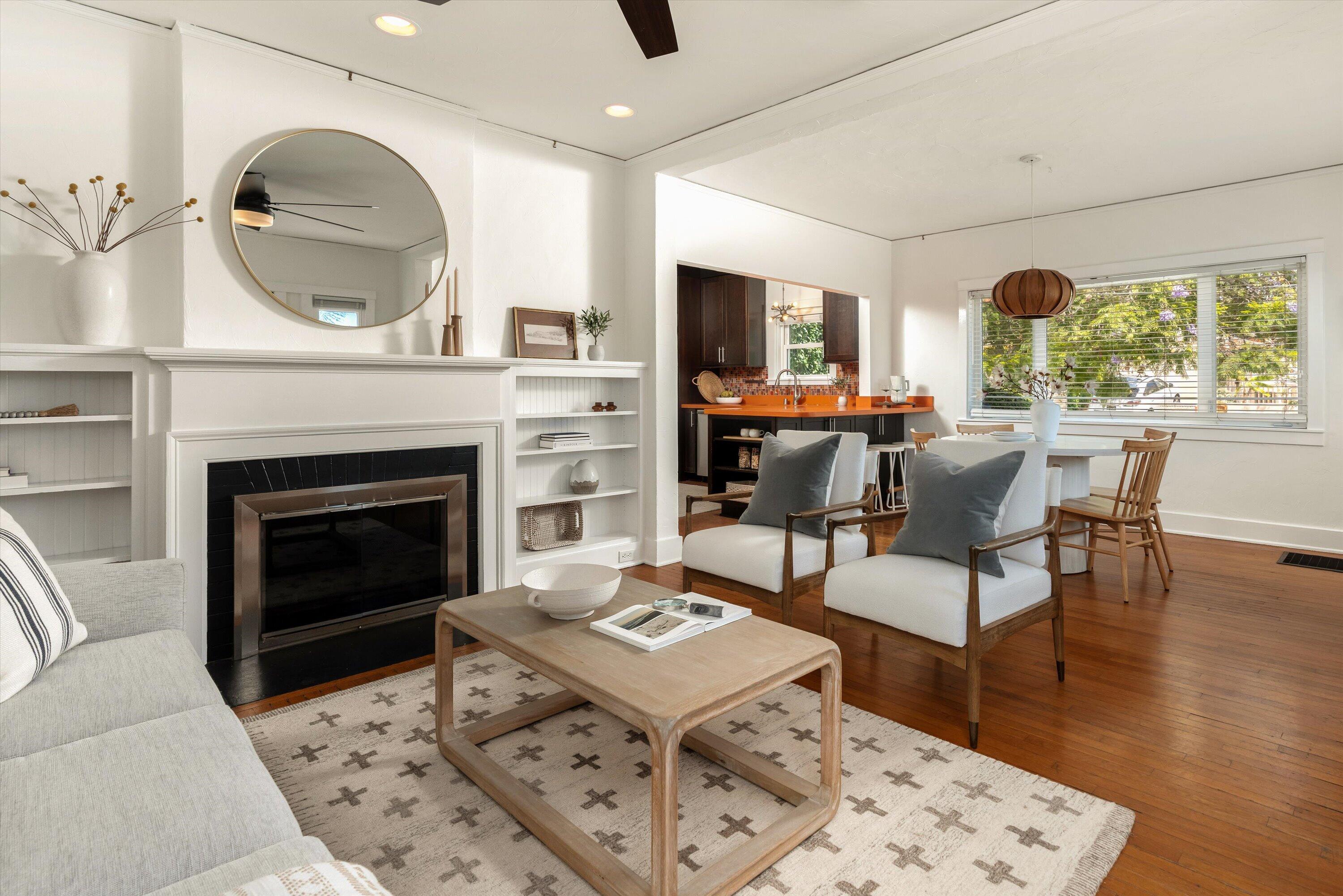 Living room with a white fireplace and built-in shelves opening onto the dining area and kitchen.
