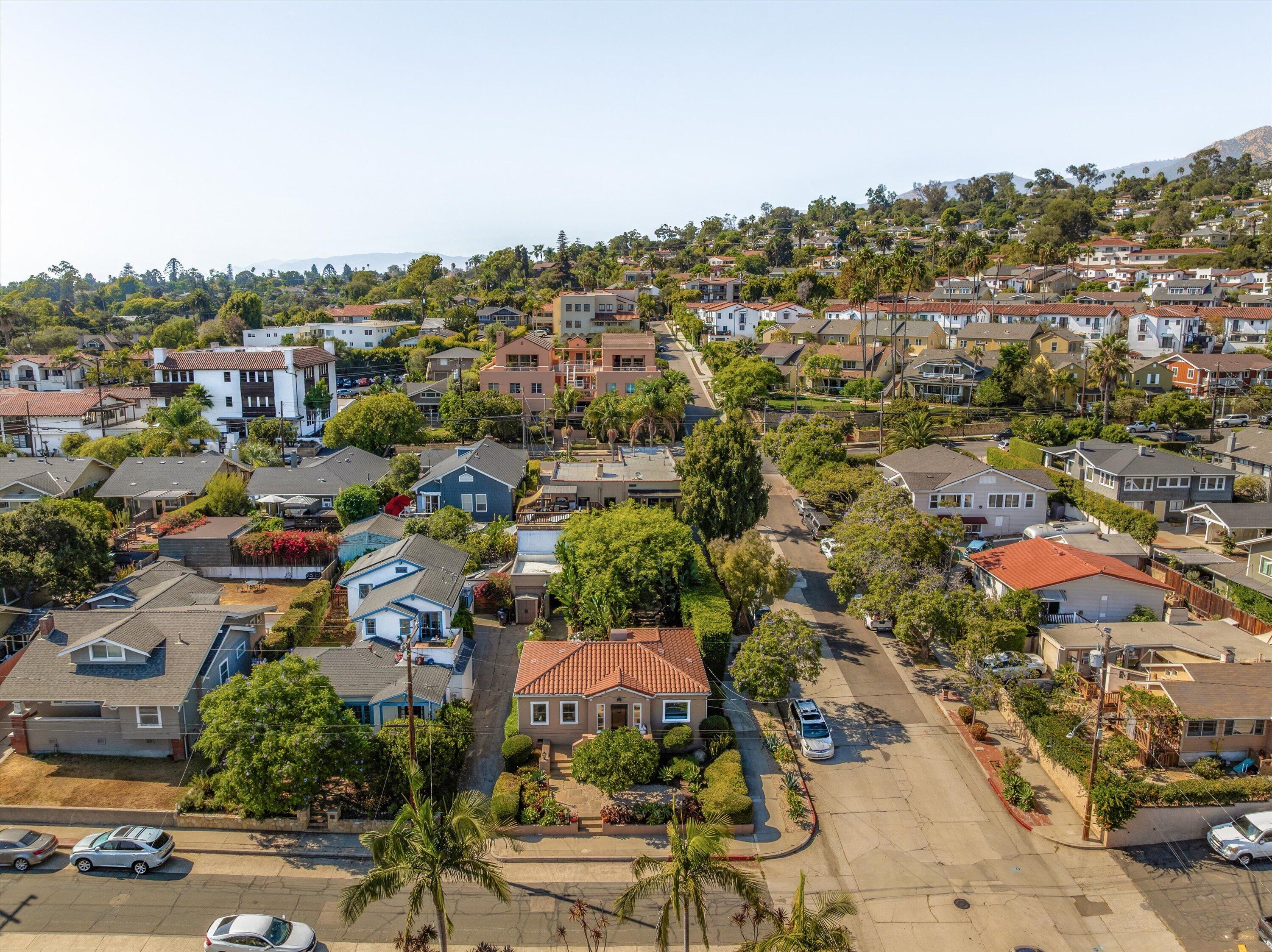 Aerial view of a tree-lined Santa Barbara neighborhood with homes and hills in the distance.