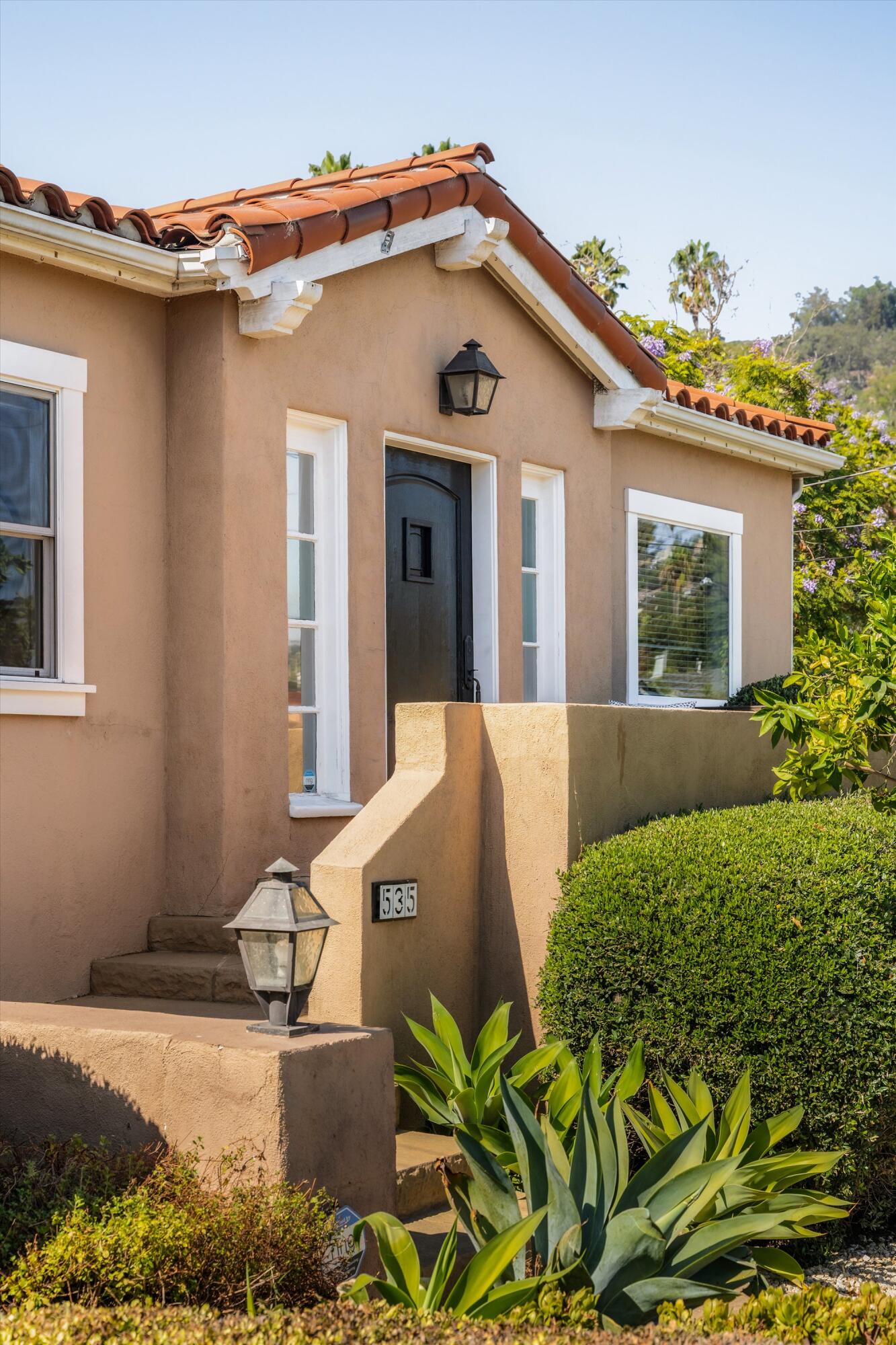 Home entrance with a terracotta tile roof, dark door, stucco entry wall, and house number 535.