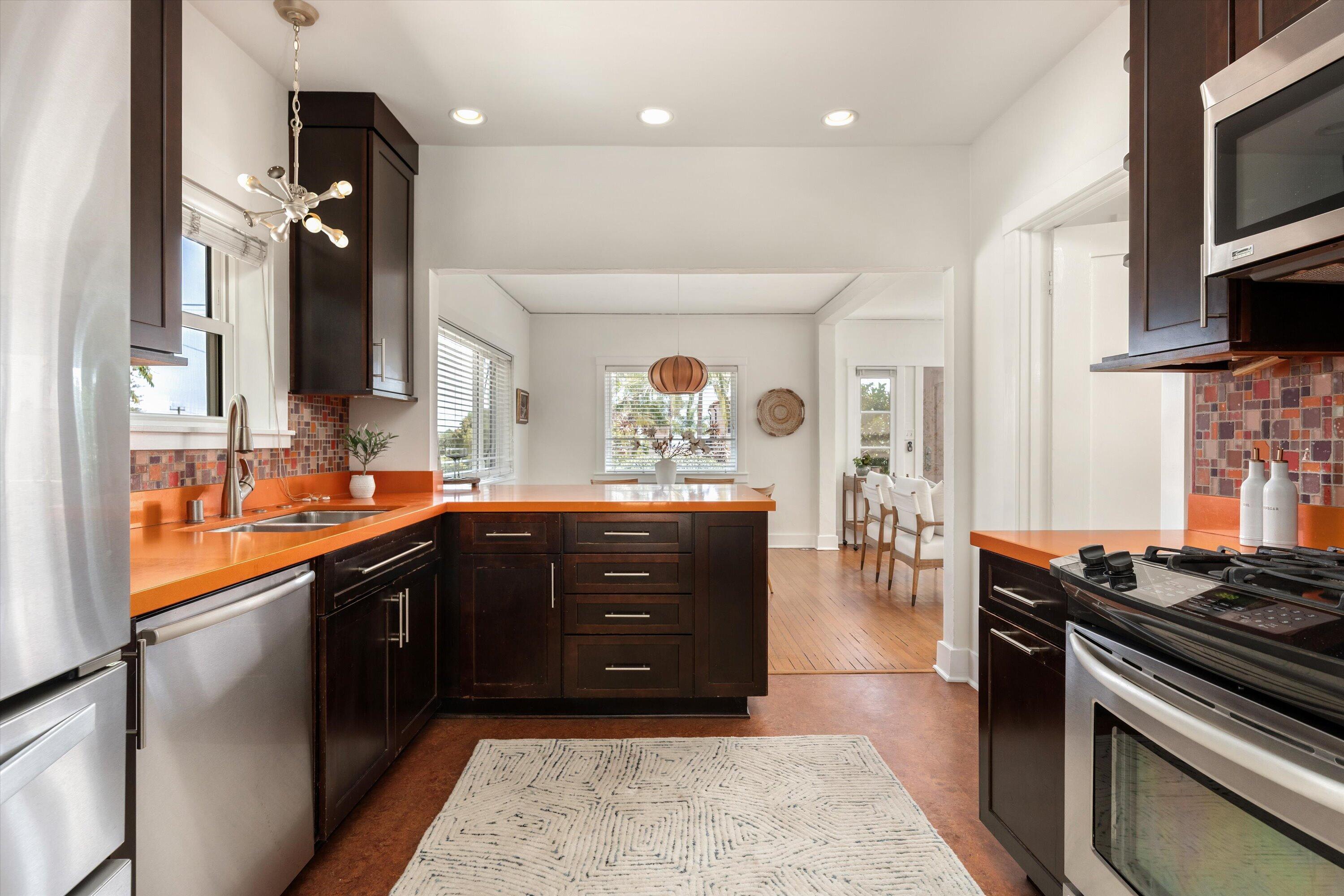 Kitchen with orange countertops, dark wood cabinetry, and a central island opening to a dining area.