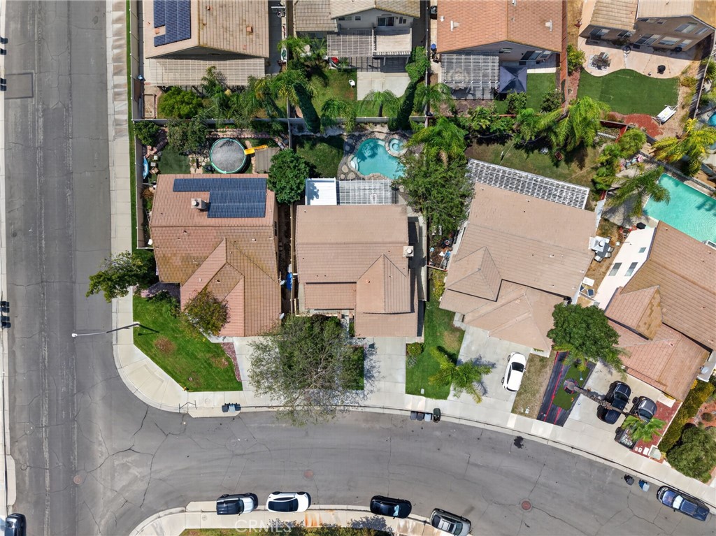 Aerial view of homes along a curved street, with backyard pools and solar panels.
