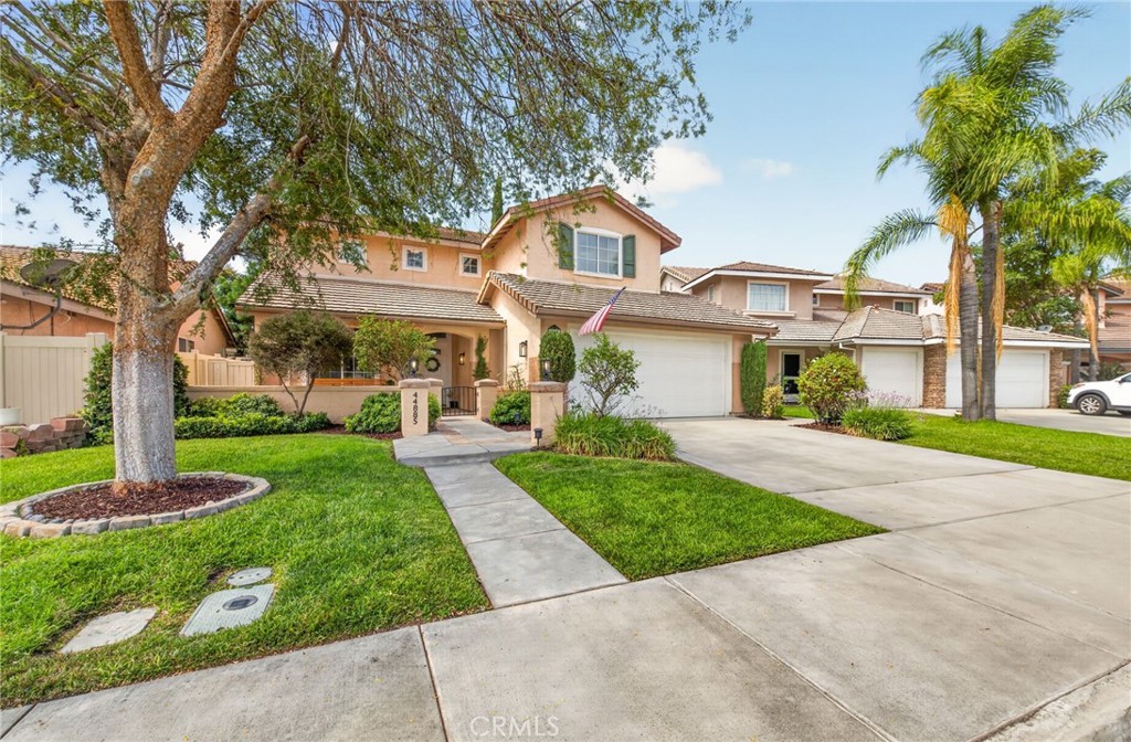 Two-story peach home with an attached garage, broad driveway, and landscaped front lawn.