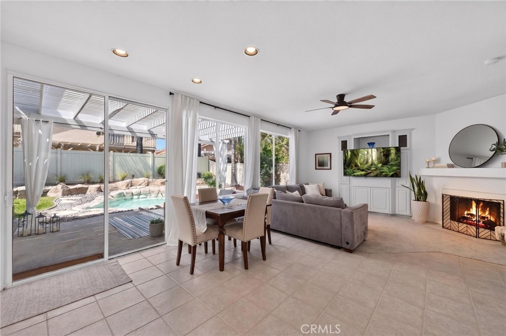 Living and dining room with a fireplace and sliding doors overlooking a backyard pool.