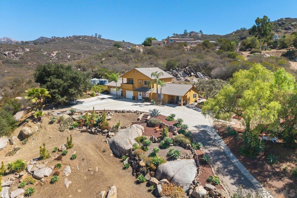 Tan home with a broad driveway and rock landscaping on a dry, hilly lot.