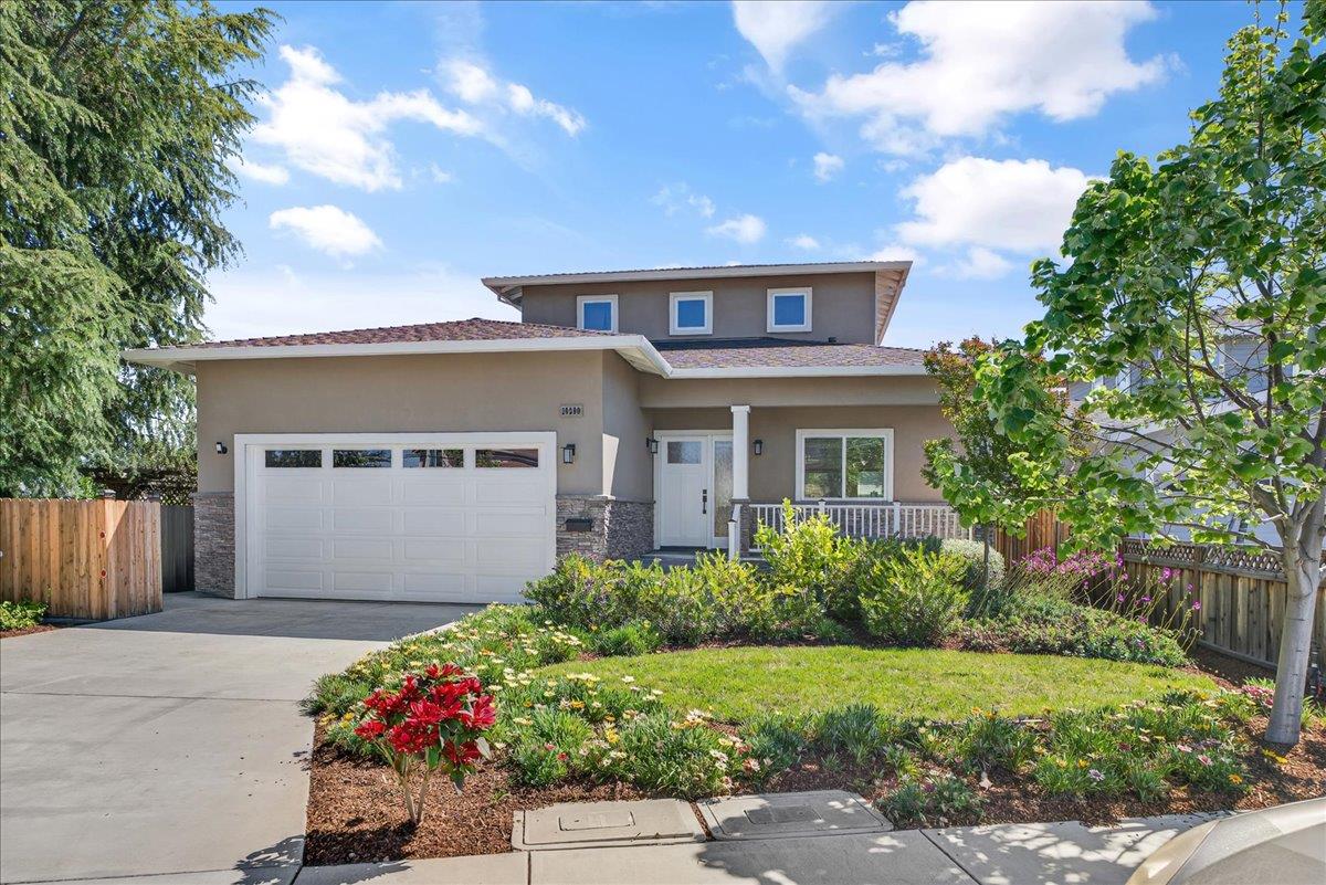 Two-story gray home with a double garage, covered porch, and landscaped front yard.