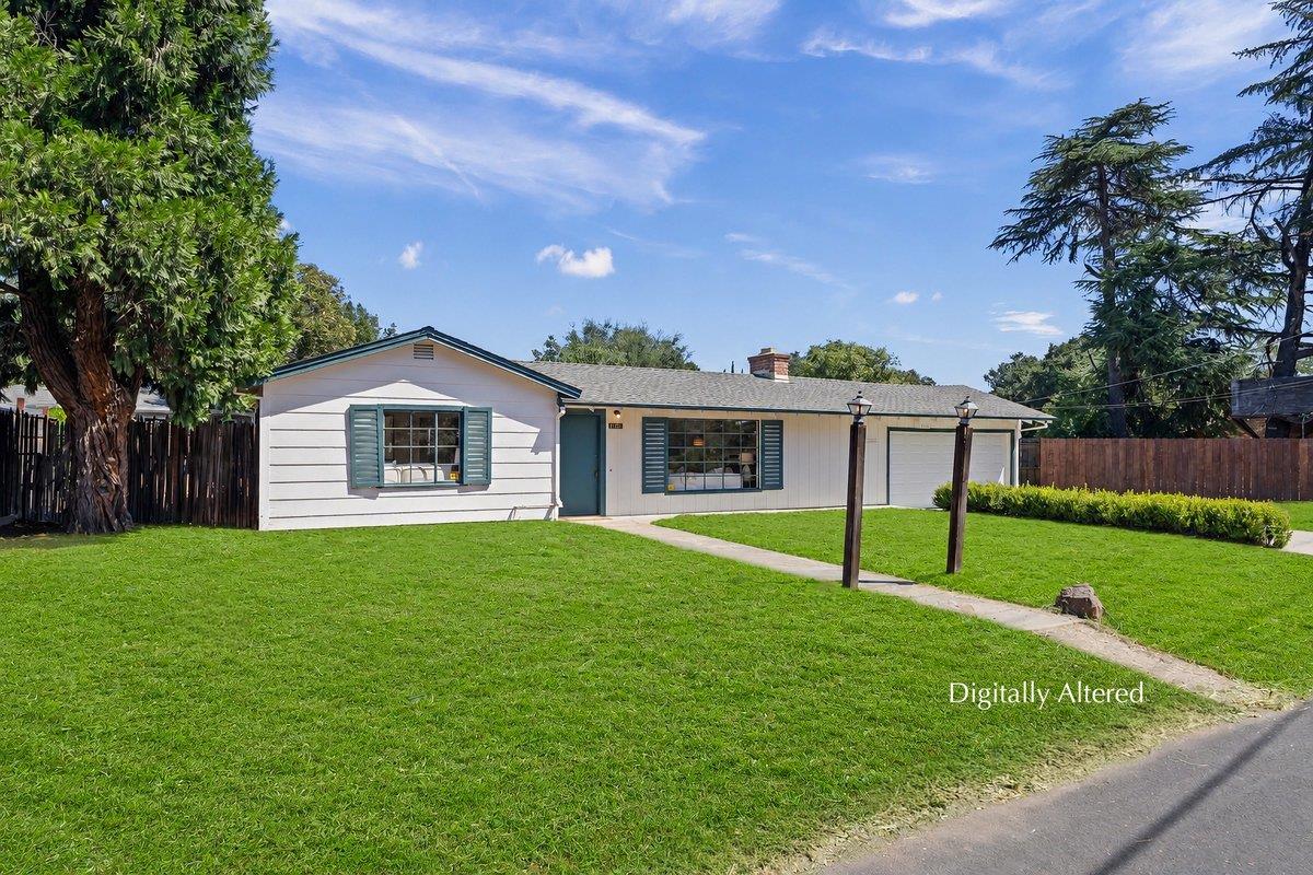 Single-story white home with blue-green shutters, an attached garage, and a broad front lawn.