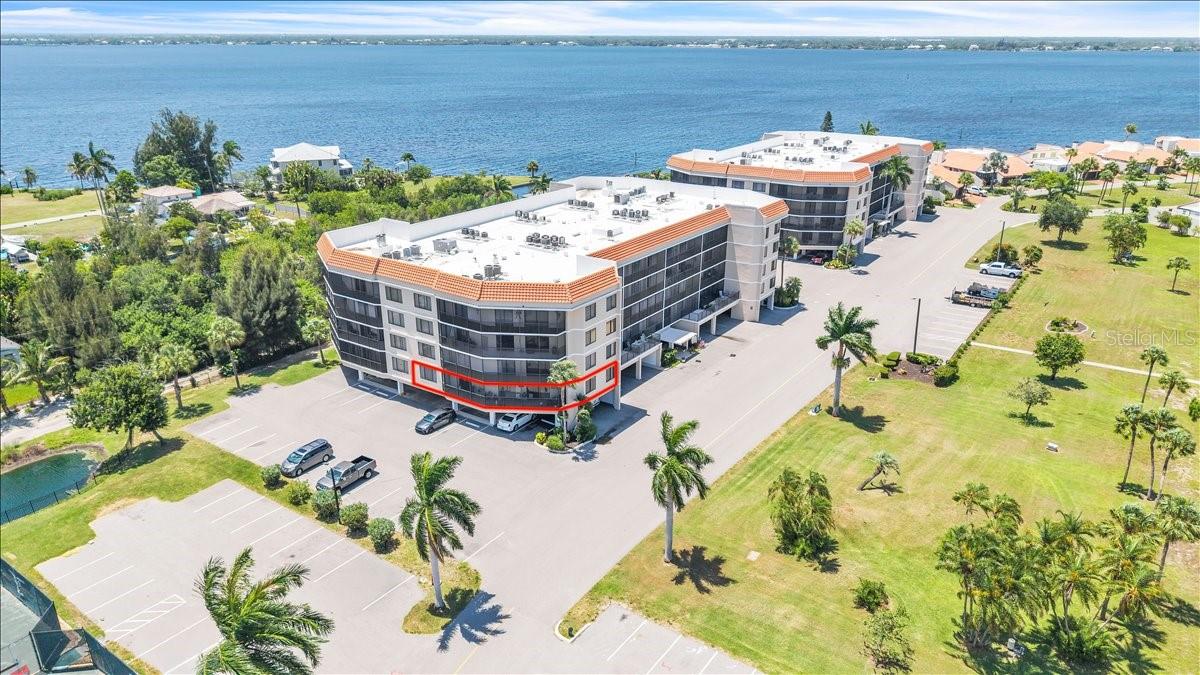 Waterfront condominium complex with a ground-floor unit outlined in red.