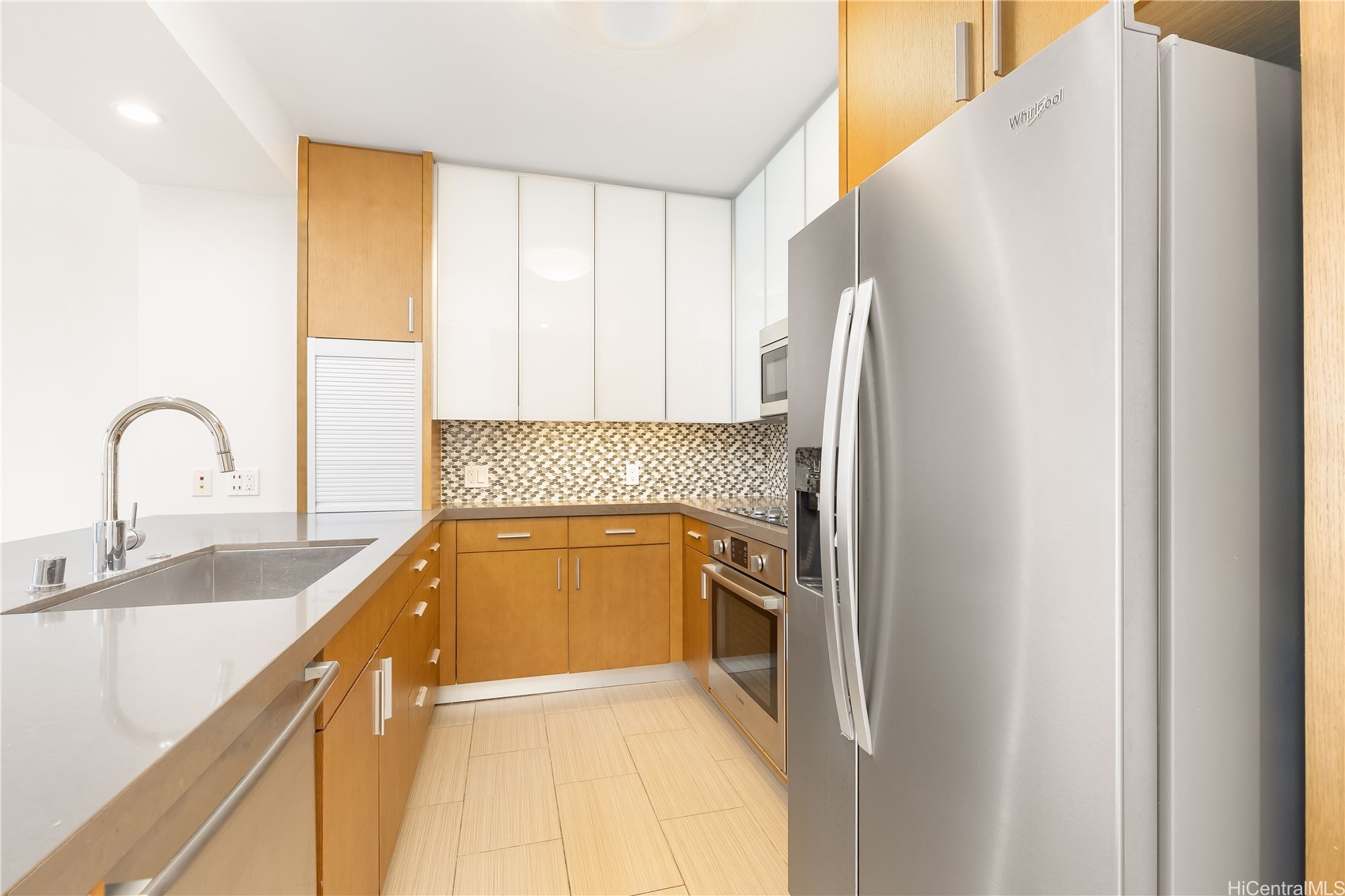 Kitchen with warm wood cabinets, mosaic backsplash, and stainless steel appliances.