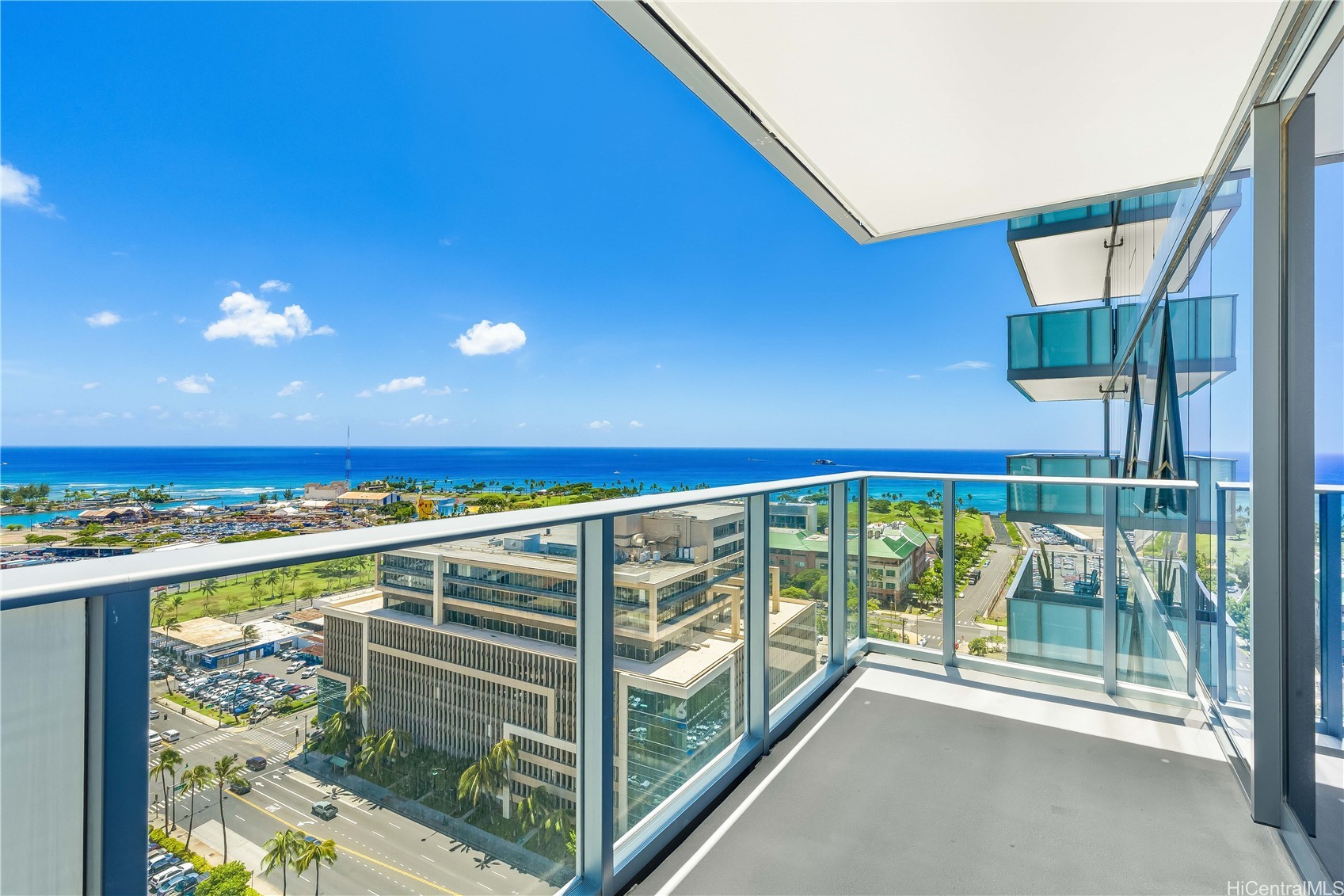 High-rise balcony with glass railings overlooking Honolulu and the ocean.