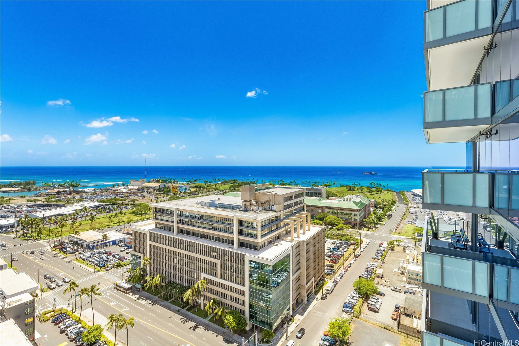 Honolulu cityscape and Pacific Ocean viewed past glass balconies from a high-rise.