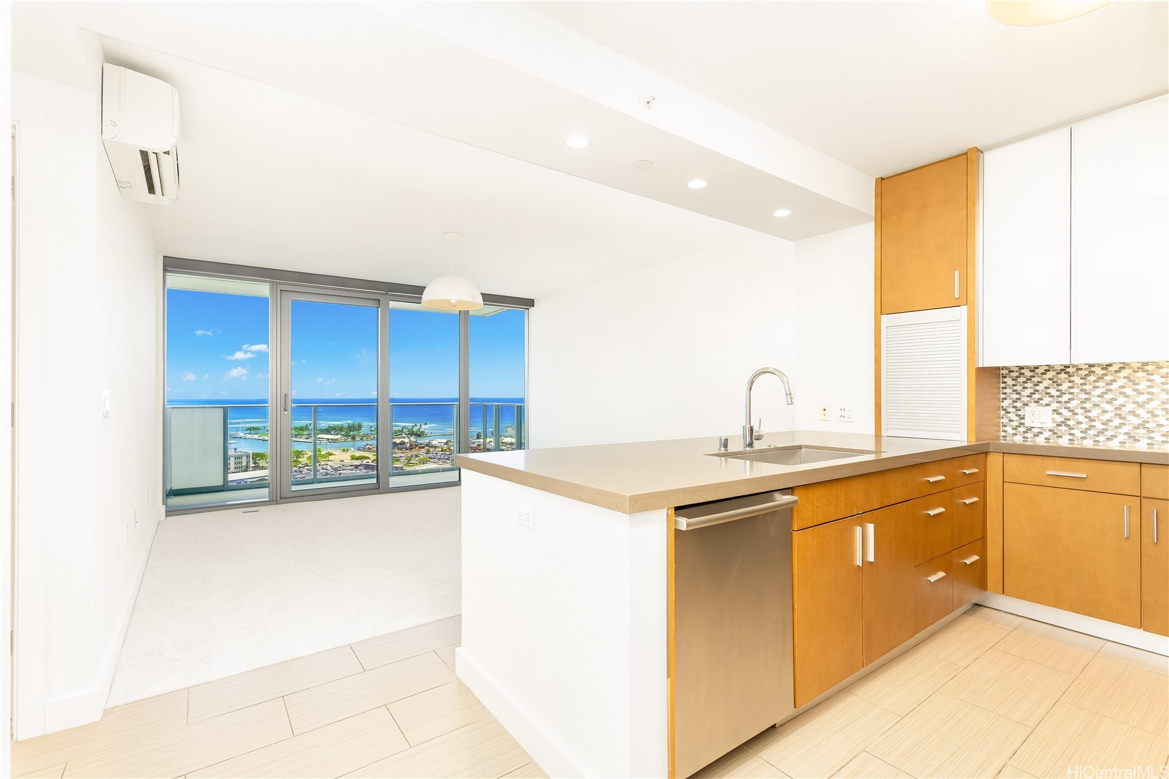 Condo kitchen with wood cabinetry and island, overlooking the ocean through sliding glass doors.