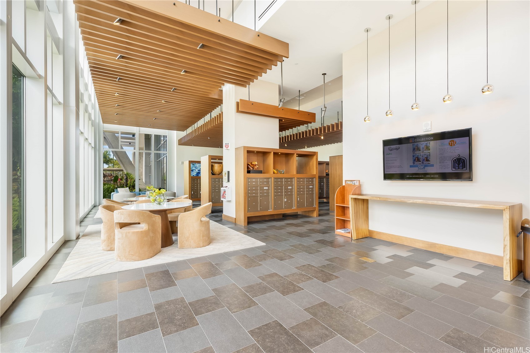 Condominium lobby with a wood-slat ceiling, mailboxes, and a seating area beside floor-to-ceiling windows.