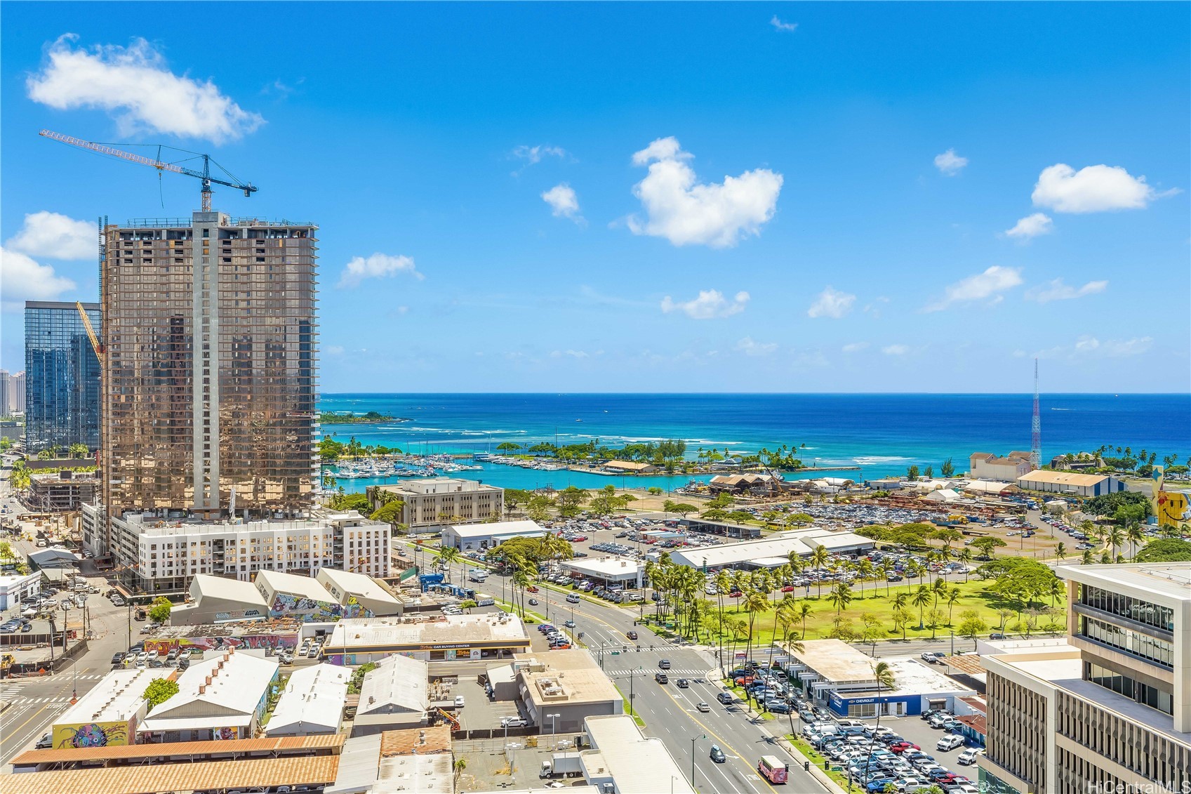 Honolulu waterfront view with the marina, Pacific Ocean, and a high-rise under construction.