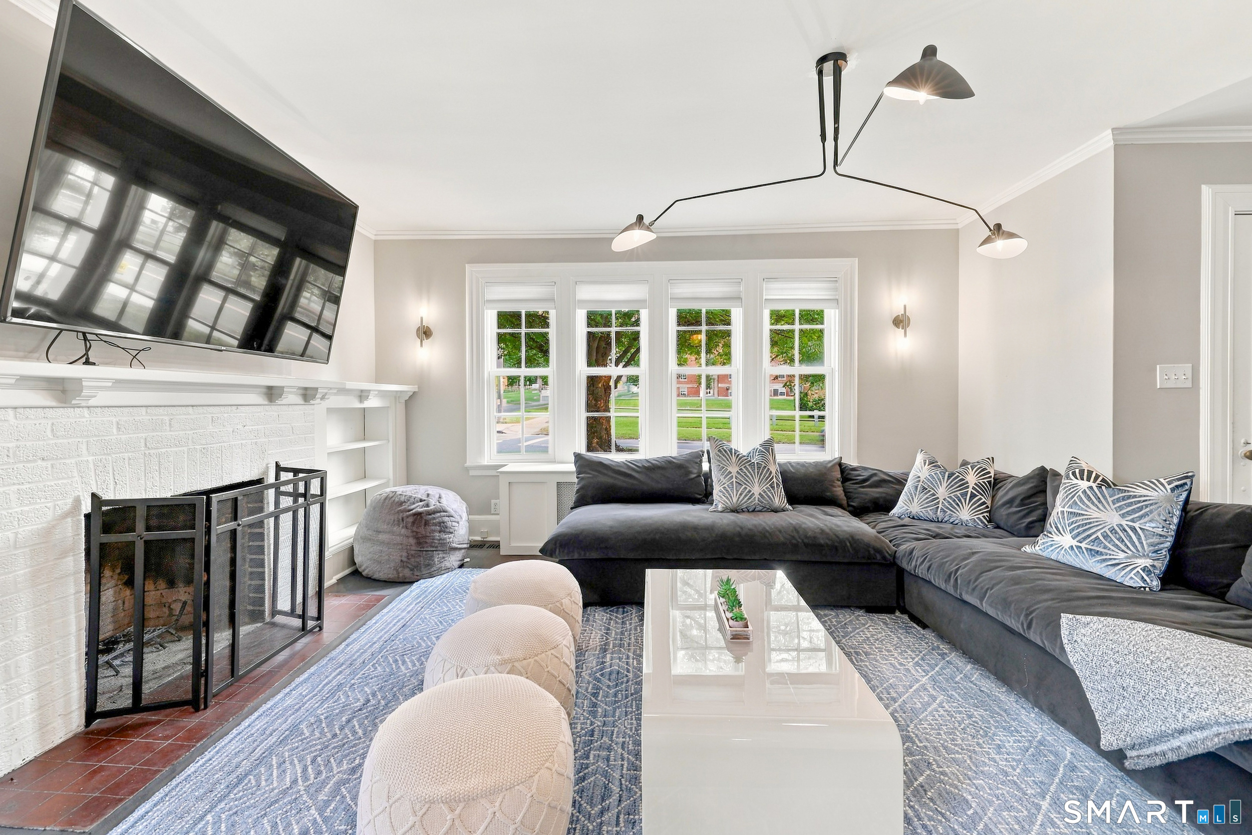 Living room with a white brick fireplace, dark sectional, and large windows.