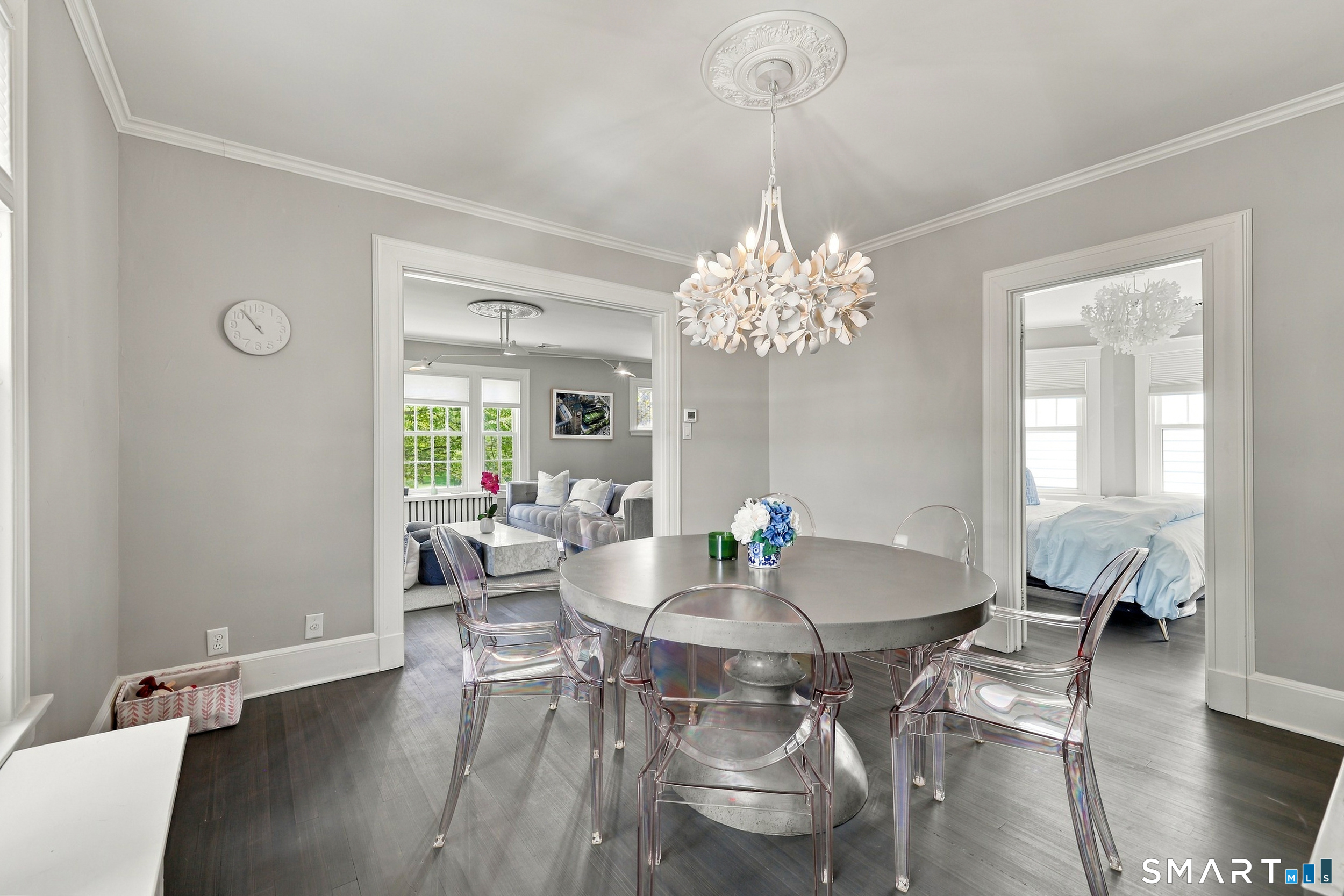 Dining room with a round table, transparent chairs, and a sculptural chandelier