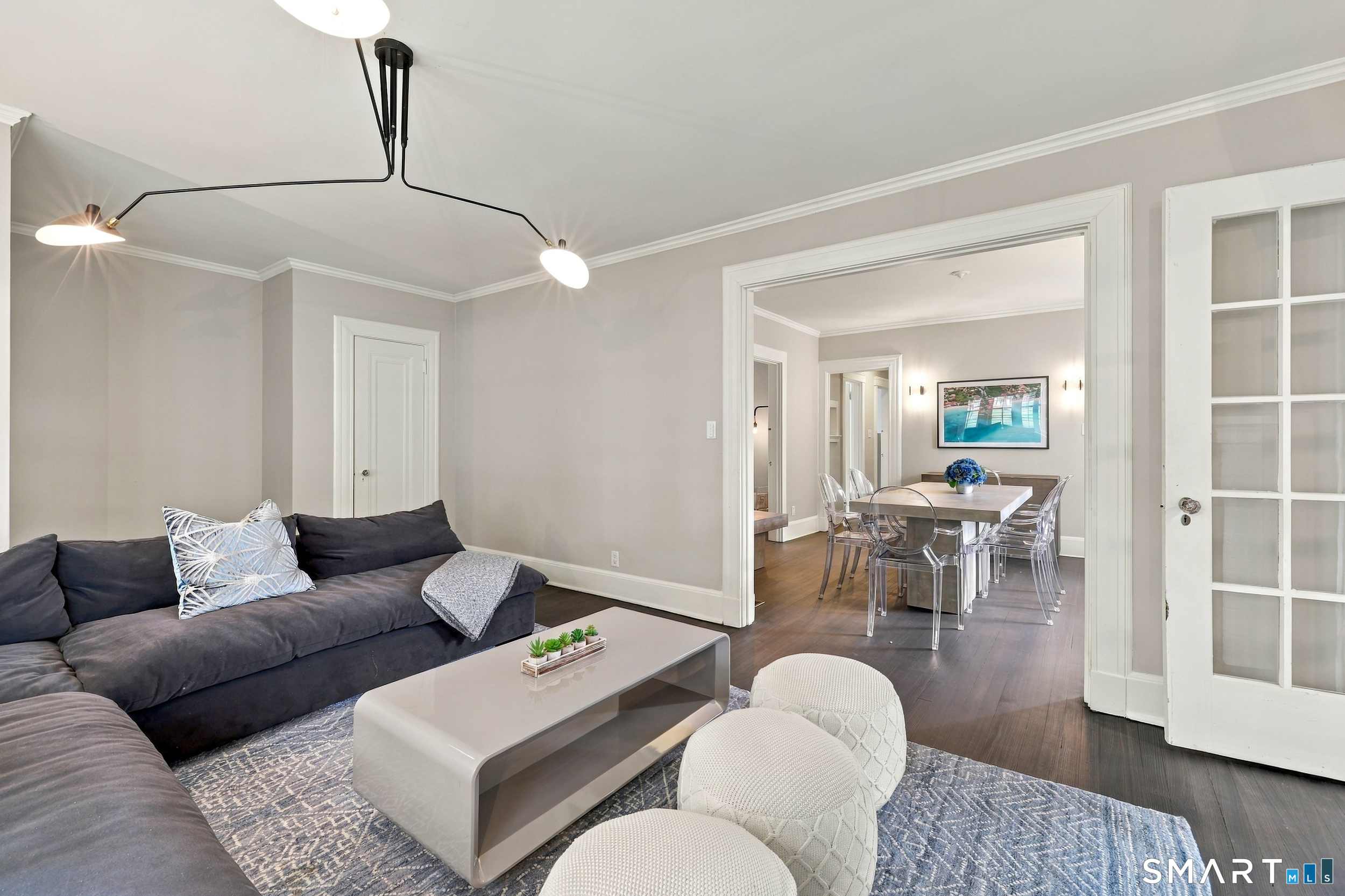 Staged living room with a dark sectional and a wide opening to the dining room.