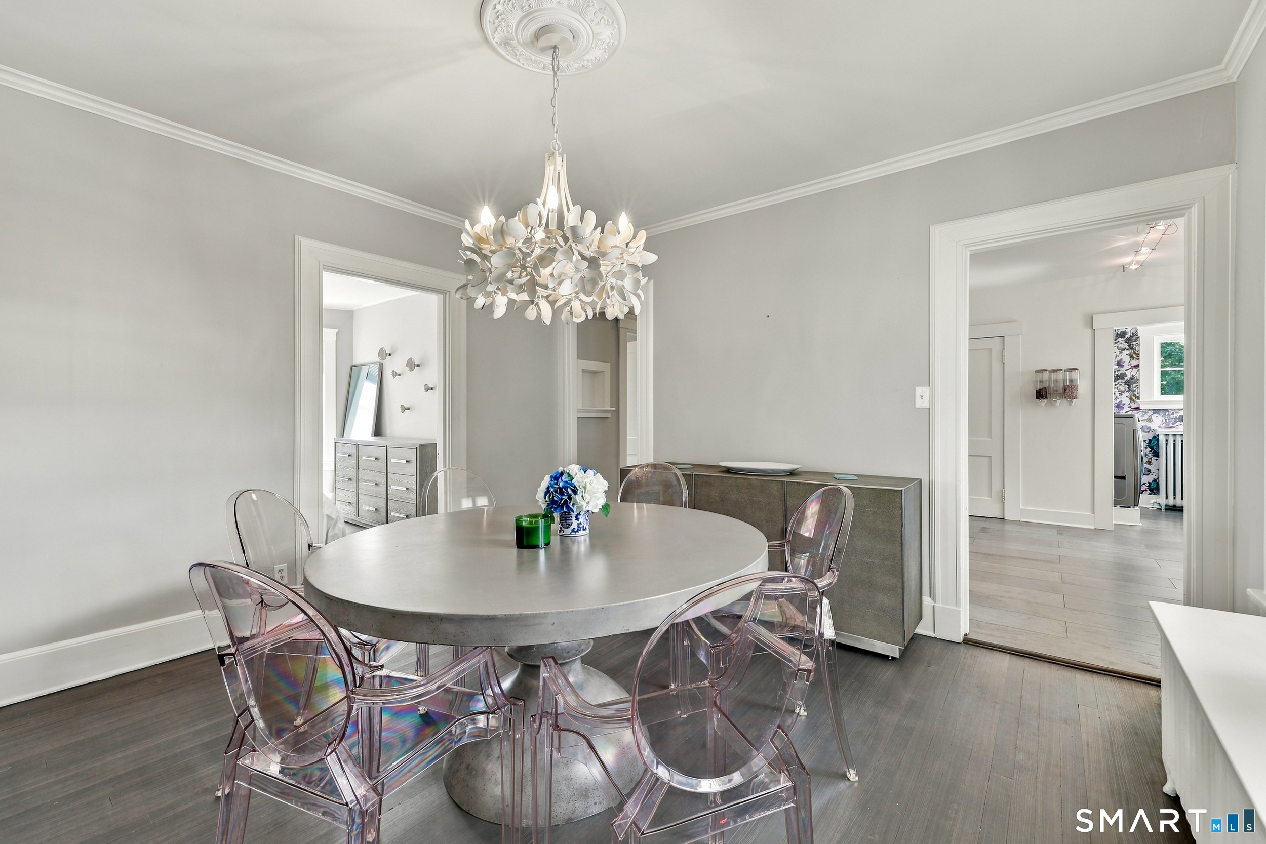 Dining room with a round table, clear chairs, and a sculptural chandelier.