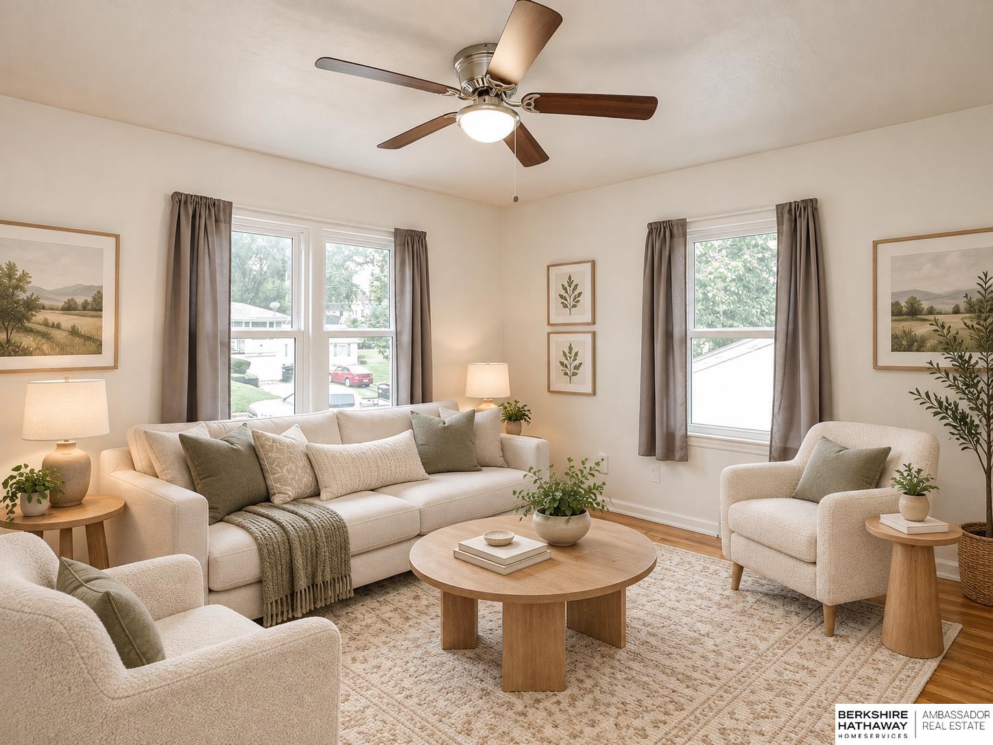 Furnished living room with a cream sofa, round wood coffee table, patterned rug, and large curtained windows.