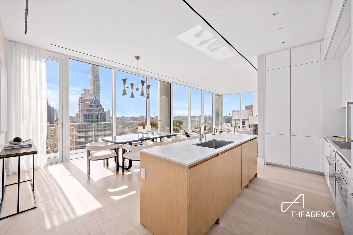 Modern kitchen and dining area with a wood island and floor-to-ceiling city-view windows.