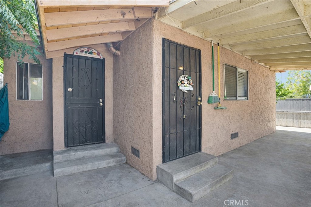Stucco home exterior with two black entry doors beneath a covered porch.