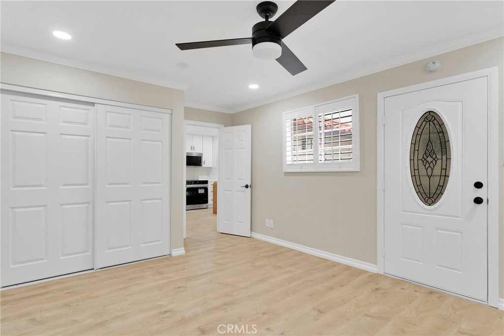 Empty entryway with light wood flooring, white closet doors, and a decorative-glass front door.