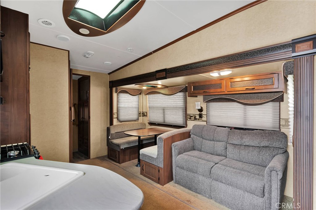 RV living area with a gray sofa, booth dinette, and compact kitchen counter.