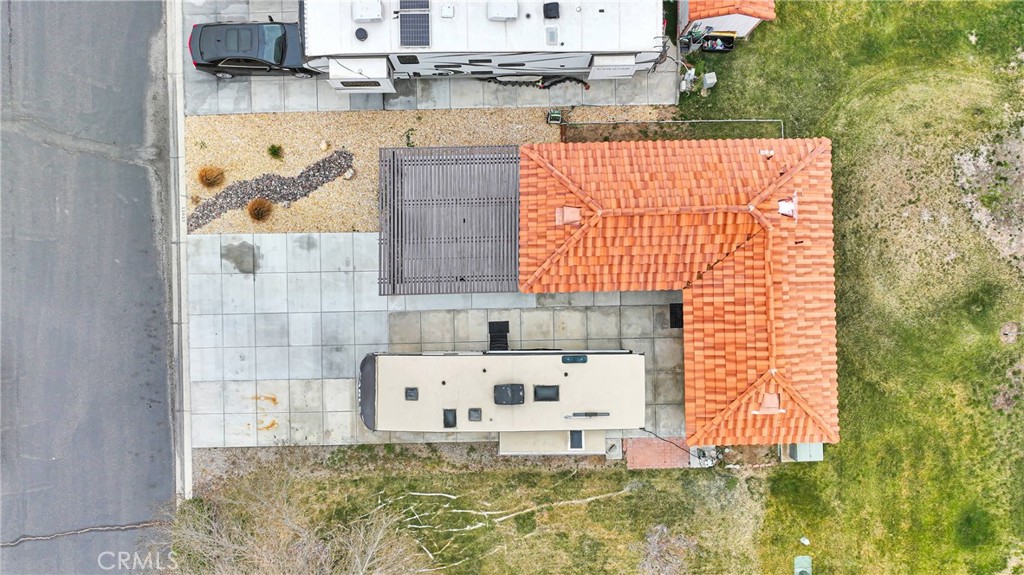 Aerial view of a home with a terracotta tile roof, RV parking, and dry landscaping.