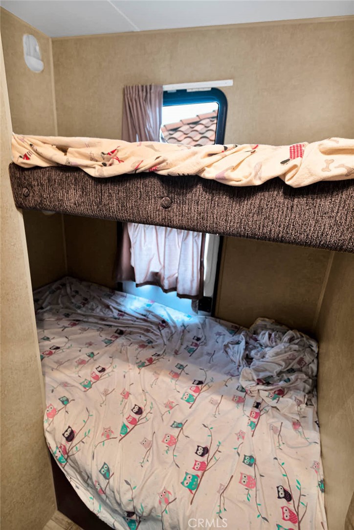 Bunk bed with colorful owl-patterned bedding and a small curtained window.