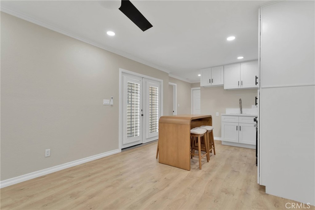 Kitchen with white cabinets, light wood floors, and a wood island with bar stools.
