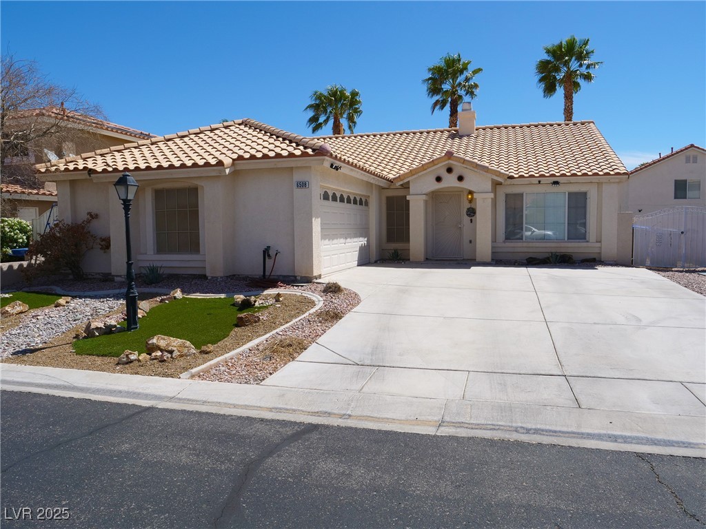 Single-story stucco home with a tiled roof, attached garage, and wide driveway.