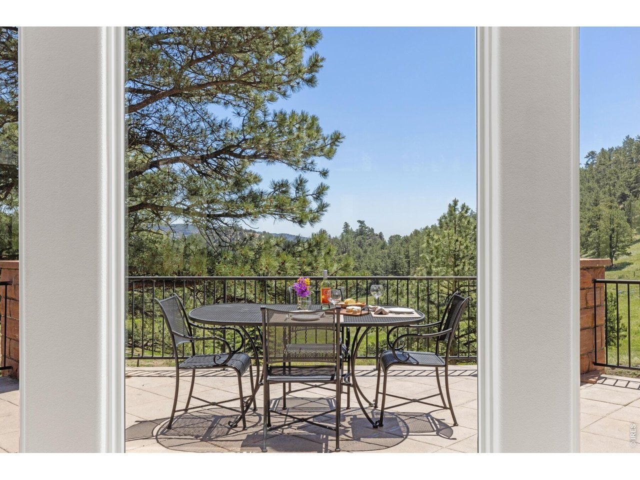 Patio dining set overlooking pine-covered hills, seen through an open doorway.