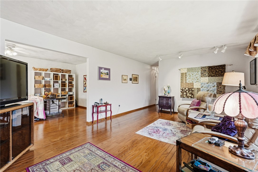 Living room with hardwood floors, recliners, patterned rugs, and a patchwork quilt wall hanging.