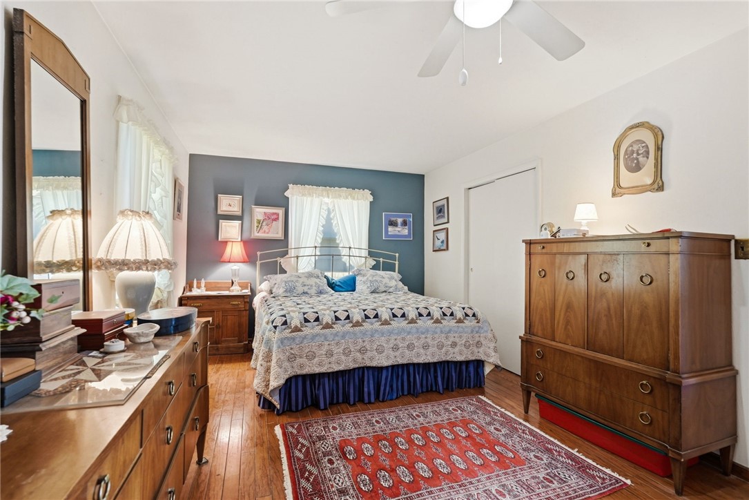 Bedroom with a bed against a blue-gray accent wall and a red patterned rug on hardwood floors.