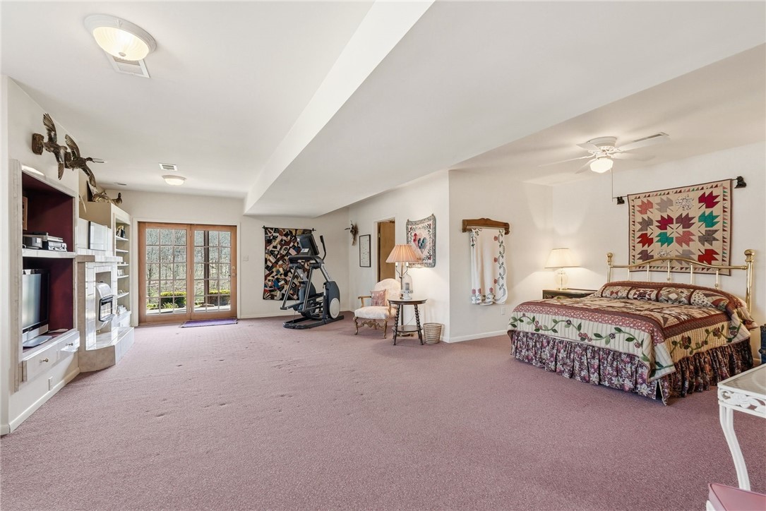 Spacious bedroom with a brass bed, patchwork quilt, mauve carpet, and exercise equipment by glass doors.