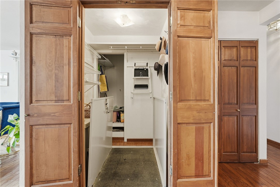 Walk-in closet with white wire shelving, stored items, and wide wood-paneled doors.